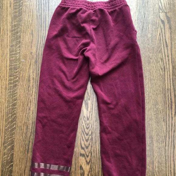 These are red sweatpants with two gold stripes. - Picture 2 of 4